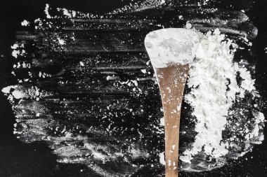 siyah arka plan üzerinde pişirme kaşık üzerinde beyaz un.