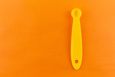 turuncu arka plan üzerinde plastik ölçüm kaşığı.