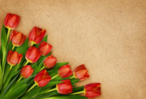 クラフトペーパーの隅に赤いチューリップの花の花束 — ストック写真