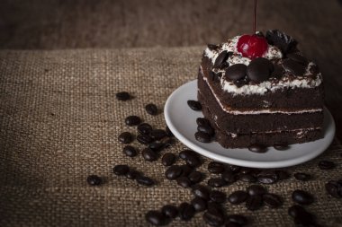 Kara Orman kek kiraz beyaz plaka ve kahve çekirdekleri koyarak Tepesi yanında yerleştirilir. Çuval çanta ve ahşap arka plan