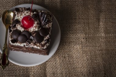Kara Orman kek kiraz, çikolata ve kaşık Tepesi altın çuval torba arka plan üzerinde beyaz tabakta koyarak renk