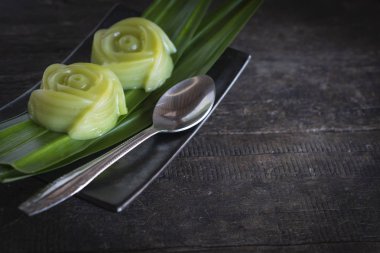 Pandanus amaryllifolius koyarak Tay tatlılar katman tatlı pasta yaprak ve siyah plaka gel ve gümüş kaşık yanında masa ahşap arka plan üzerine koyarak