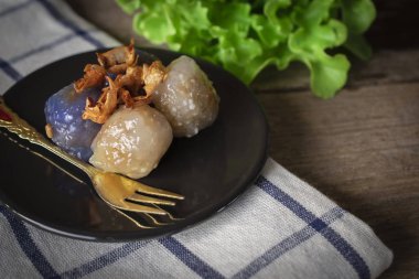 Sagopa kajmer domuz kızarmış sarımsak toping ile daire siyah plaka var marul yer arka ve altın çatal masa örtüsü ve ahşap arka plan üzerinde siyah plaka üzerine yerleştirin