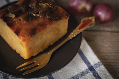 Mung fasulye daire siyah plaka koymak ile Tay muhallebi var altın çatal siyah plaka sağ el ve soğancık yer arka masa örtüsü ve ahşap zemin üzerine yerleştirin