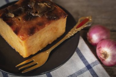 Mung fasulye daire siyah plaka koymak ile Tay muhallebi var siyah plaka sağ el üzerinde altın çatal yer ve masa örtüsü ve ahşap zemin üzerine yanında soğancık yerini
