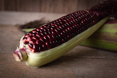 Siam Ruby kız kırmızı renk ile süper tatlı Mısır, taze yenebilir yer örtüşme ve yer ahşap masa arka plan üzerinde