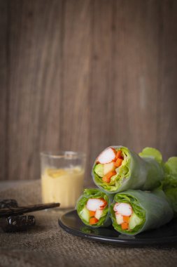 Salata yemek çubukları ve salata sosu yanında yerleştirilen bir çuval yerleştirilen siyah plaka üzerinde rulo.