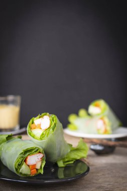 Bir wooder masada yer siyah plaka salata rulo olduğunu yemek çubukları, beyaz plaka ve salata sosu arka yerleştirilen salata rulo.