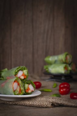 Salata domates ve biber yanında yerleştirilen bir çuval yerleştirilmiş beyaz plaka üzerinde rulo ve salata arka yerleştirilen siyah plaka üzerinde rulo.