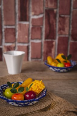 Beyaz ve mavi çizgili bir tabakta Tay tatlılar çuval ve ahşap masa orada benzer nesne ve arka ve önüne yerleştirilen çatal beyaz Kupası yer yerleştirilen.