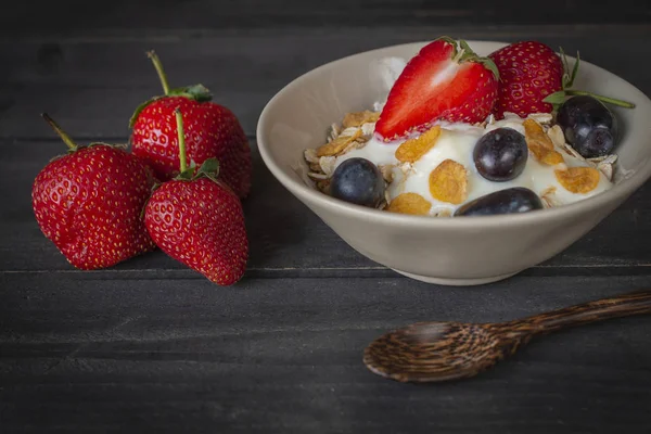 酸奶混合燕麦片 草莓和葡萄在白色碗在木桌上与勺子和草莓放在周围 — 图库照片