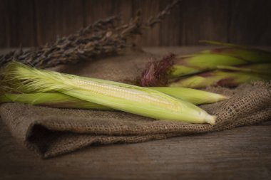 Taze olgun bebek Mısır sepet çuval ve ahşap masa arka plan üzerinde orada arka yüzünde yerleştirilen bebek Mısır mı.