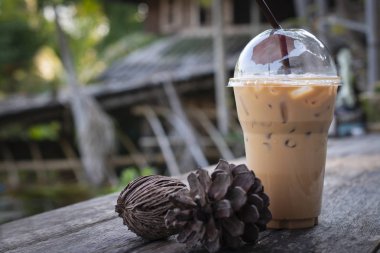 Buzlu kahve içecek ile kurutulmuş çam kozalakları eski ahşap ev arka plan karşı ahşap tablo