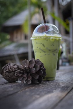 Buzlu süt yeşil çay içecek ile kurutulmuş çam kozalakları ahşap tablo 