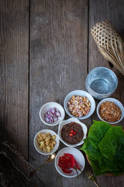 Miang kham， 皇家叶包装开胃菜包括沙洛， 姜， 炒豆， 柠檬片， 槟叶， 辣椒， 炒椰子和辣椒酱， 整体放在木桌上. — 图库照片