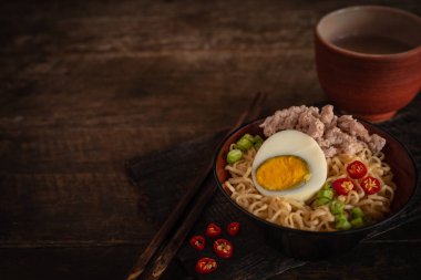 Odun masada siyah kase üzerinde domuz eti, yumurta ve sebze ile Anlık erişte var biber, çubuk ve içme cam etrafında yerleştirilir.