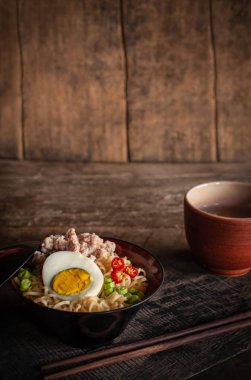 Odun masada siyah kase üzerinde domuz eti, yumurta ve sebze ile Anlık erişte orada çubuk ve içme cam etrafında yerleştirilir.