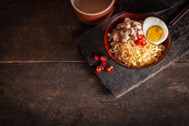 Odun masada siyah kase üzerinde domuz eti, yumurta ve sebze ile Anlık erişte var biber, çubuk ve içme cam etrafında yerleştirilir.