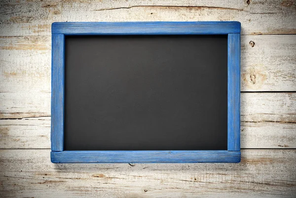 挂在旧木墙上的蓝色木框架黑板 — 图库照片