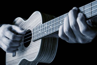zebrawood siyah arka plan, mavi görüntü üzerine yapılmış güzel bir ukulele oynarken müzisyen elleri