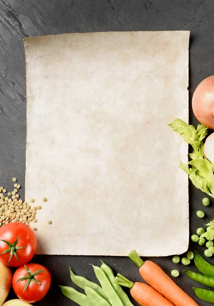 Oud papier vel met groenten op zwarte leisteen, bovenaanzicht — Stockfoto
