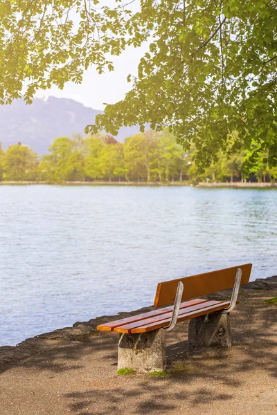 Red bench under cherry blossom tree near lake and mountain — Stock Photo, Image