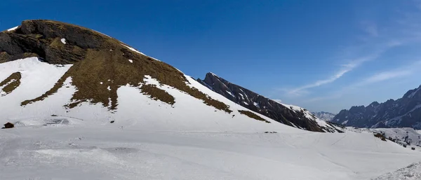 最初はスキー場の高い山と雪の上の茶色の乾いた草 — ストック写真