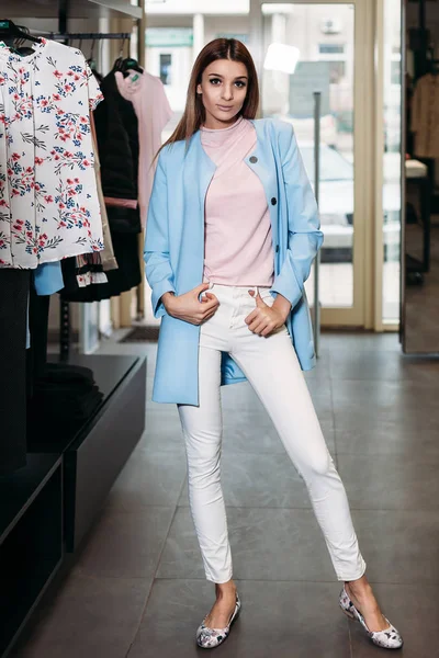 Beautiful model brunette girl in stylish clothes, posing in clothing store, a new trend of clothes. Banner for a clothing store. For showrooms and fashion stores, cover stories, interior studio