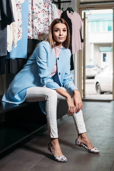 Beautiful model brunette girl in stylish clothes, posing in clothing store, a new trend of clothes. Banner for a clothing store. For showrooms and fashion stores, cover stories, interior studio