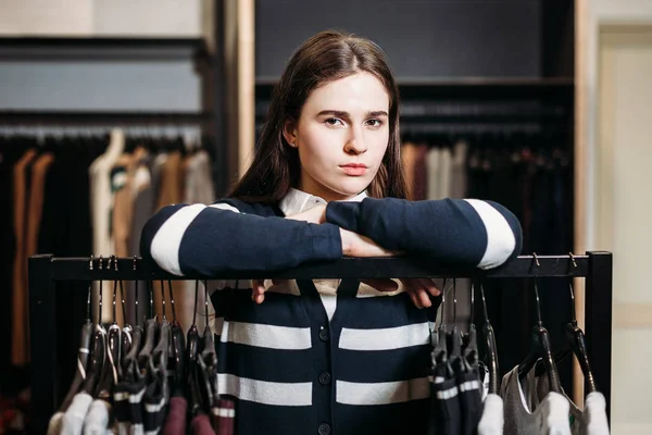 Beautiful young woman store Manager near rack with hangers