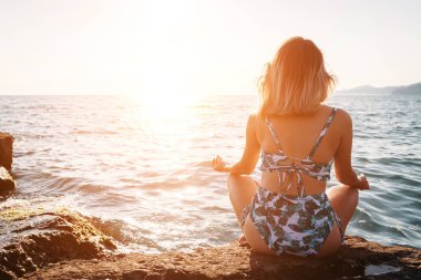 Kız Yoga sahilde günbatımı anda yapıyor. Sağlıklı yaşam tarzı.