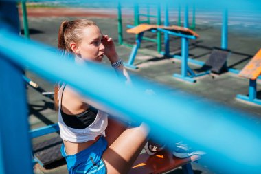 Sporcu genç sarışın kadın spor sahasında antrenmanlardan sonra dinleniyor..