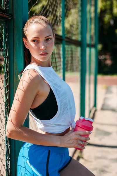 一个运动的年轻性感女人的肖像与一瓶凉水在夏季运动场 健康的生活方式理念 — 图库照片