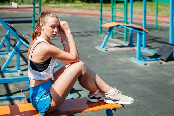 Αθλητική Νεαρή Ξανθιά Γυναίκα Κάθεται Και Ξεκουράζεται Στο Γήπεδο Κατά — Φωτογραφία Αρχείου