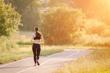 Genç bayan parkta koşuyor.