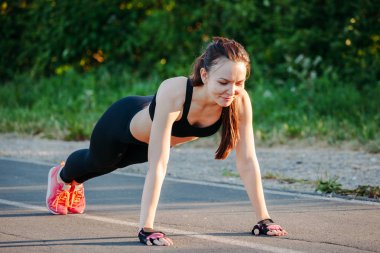 Güzel ince esmer dışarıda parkta biraz şınav. Uygun