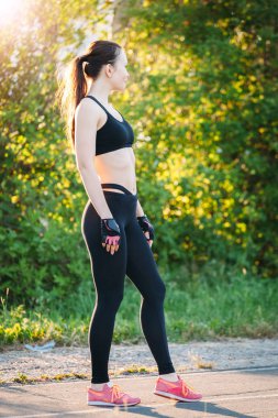 Atletik kız sokakta parkta egzersiz için hazırlanıyor