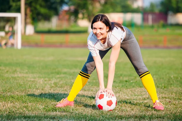 Счастливая улыбающаяся женщина с футбольным мячом на футбольном поле. проведение в — стоковое фото