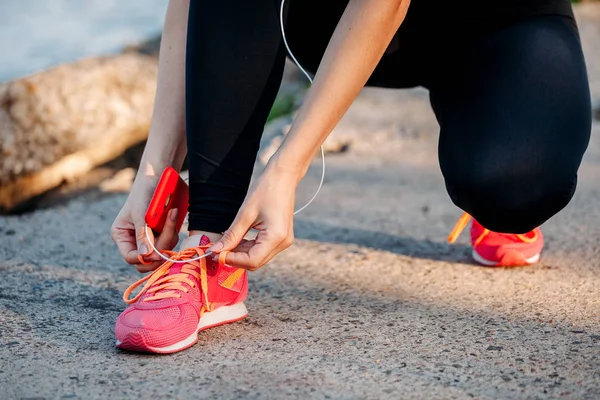 Deporte joven mujer atando cordones en zapatillas de deporte — Foto de Stock