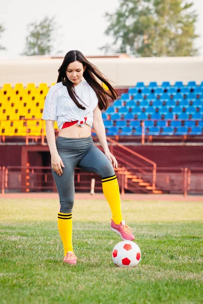 Atlético jovem sexy menina no campo de futebol com bola no ensolarado su — Fotografia de Stock