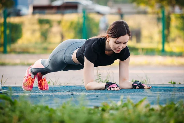 Atletisk flicka utövar planka på idrottsplats i park — Stockfoto