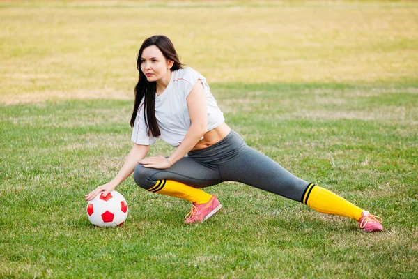 Atletica giovane ragazza sexy sul campo di calcio con palla su sole su — Foto Stock