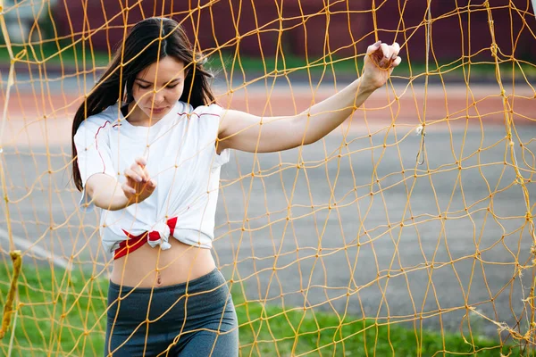 Ritratto di giovane donna sportiva con i capelli lunghi vicino alla porta del calcio — Foto Stock