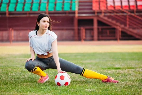 Atletica giovane ragazza sexy sul campo di calcio con palla su sole su — Foto Stock