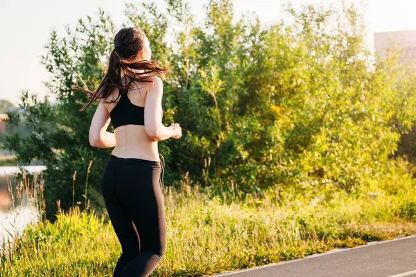 Joven mujer de los deportes que participan en la mañana de verano corriendo en el parque en — Foto de Stock