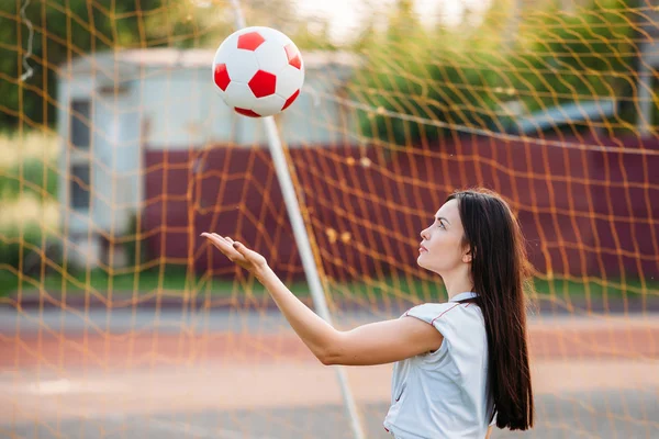 女人在网格的背景下向体育场投掷足球 — 图库照片
