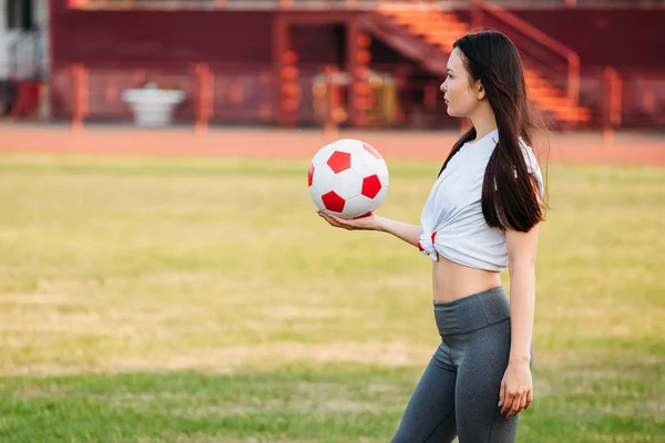 Jovem mulher de esportes com bola no campo de futebol — Fotografia de Stock