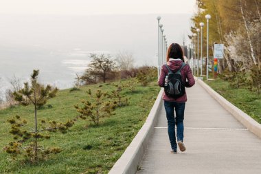 genç kadın turist Park yolu üzerinde yürüme. arka görünüm