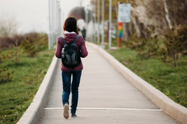 genç kadın turist Park yolu üzerinde yürüme. arka görünüm