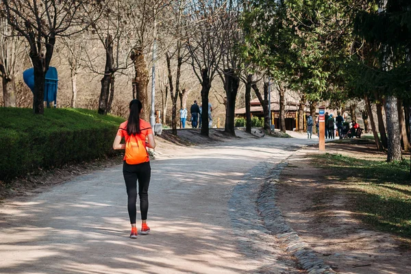 Chica turista en naranja camiseta caminando con mochila en Park on — Foto de Stock